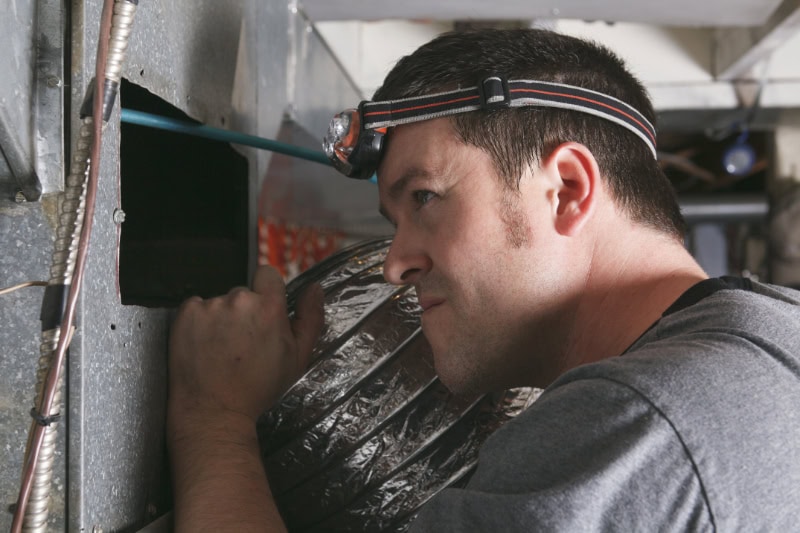 HVAC technician performing maintenance on a furnace.