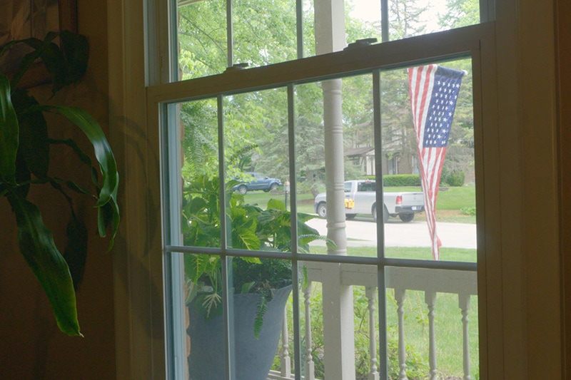 Video - Energy Saving Tip 5. Window looking out to front porch and American flag.